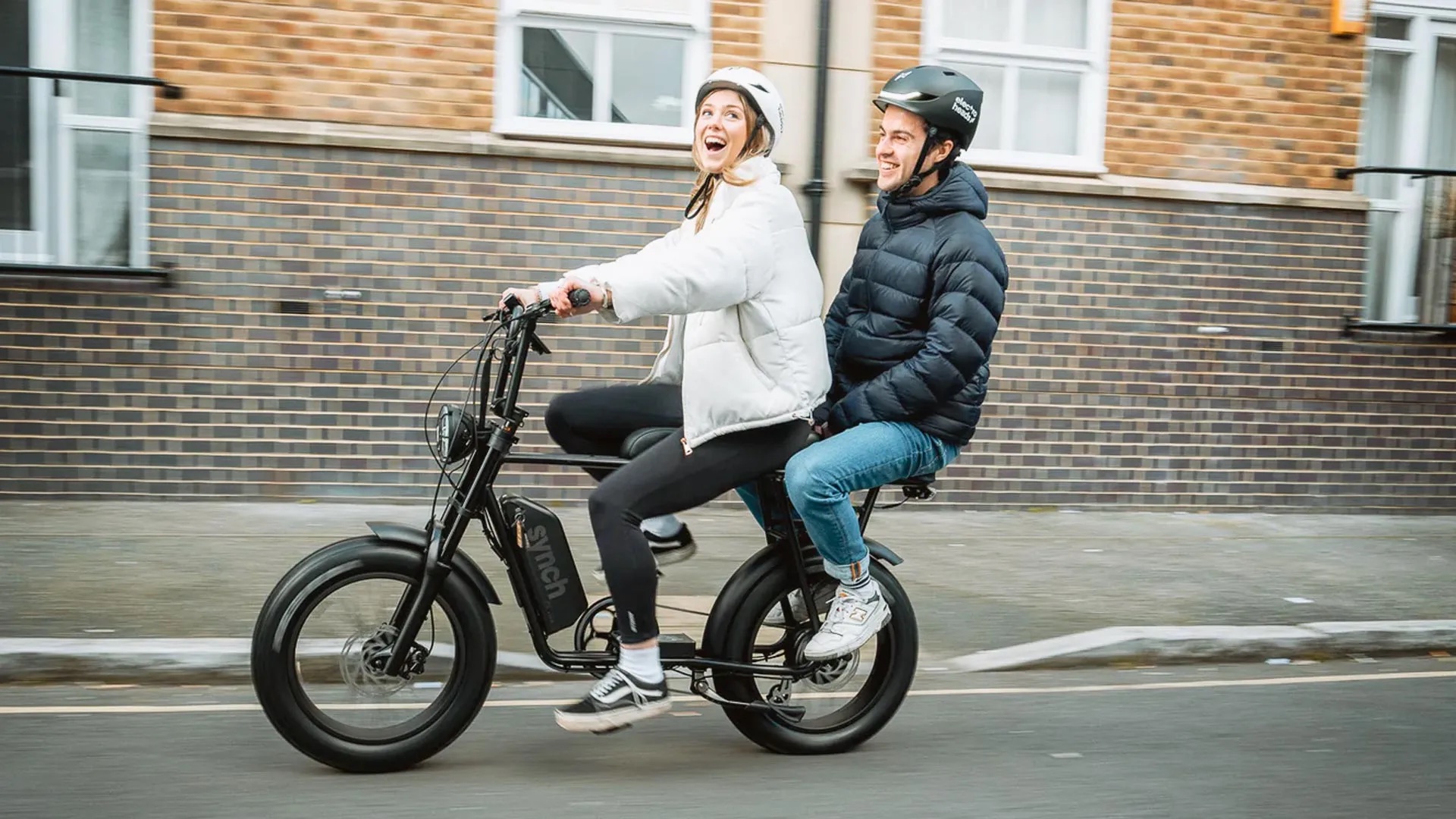 Lady and man riding on a Synch electric bike in black. Synch Electric bikes