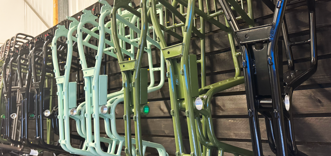 Synch electric bike frames in various black, green and blue lined up and hanging on a wall